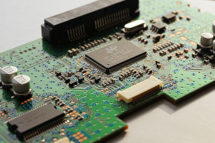 A close-up of a green circuit board with chips, representing collapsing industries in technology.