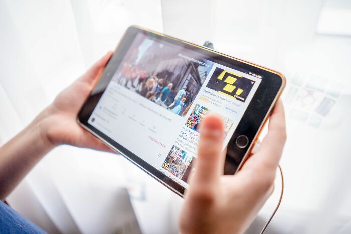 Hands holding a tablet displaying a YouTube video, highlighting changing industries and digital media.