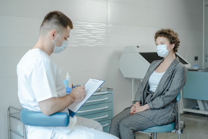 A doctor consults a masked patient in an office, illustrating industries about to collapse in healthcare.