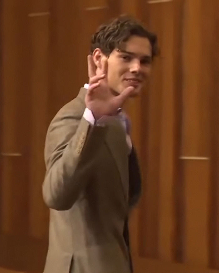 Looksmaxxing influencer Clavicular waving in a brown suit Looksmaxxing influencer Clavicular waving in a brown suit