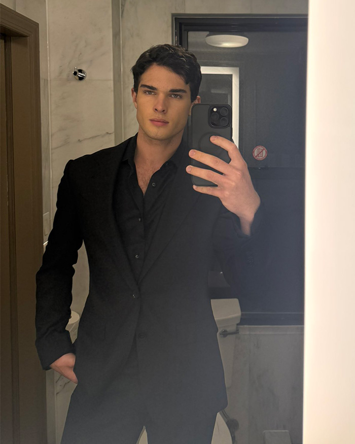 A mirror selfie of looksmaxxing influencer Clavicular dressed in a sharp black suit. A mirror selfie of looksmaxxing influencer Clavicular dressed in a sharp black suit.