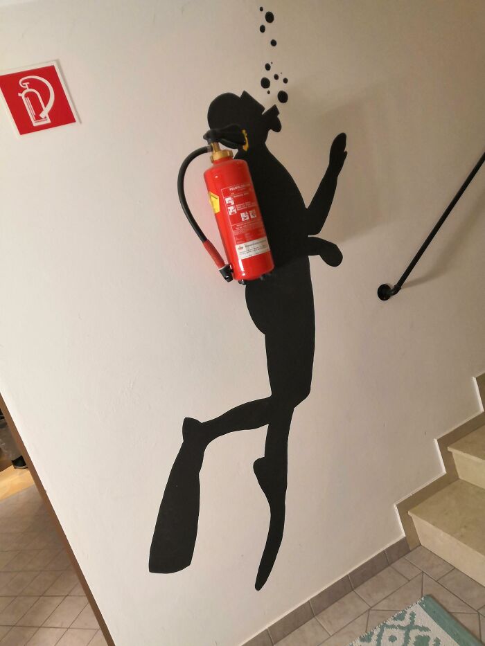 Creative fire extinguisher design resembling a diver on a wall with bubbles