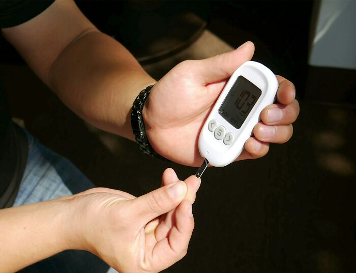 A person testing blood glucose levels, reminding of the needs of diabetic and strange patients.