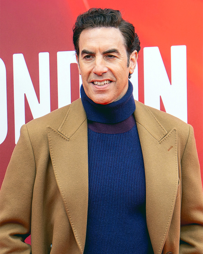 Isla Fisher dating after divorce: Sacha Baron Cohen smiling in a turtleneck and coat.