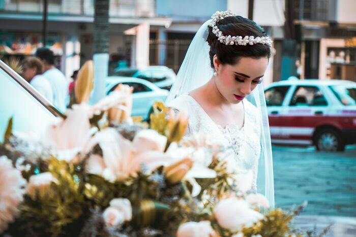 A beautiful bride in a white gown and veil looks down, perhaps reflecting on going no contact with a parent.