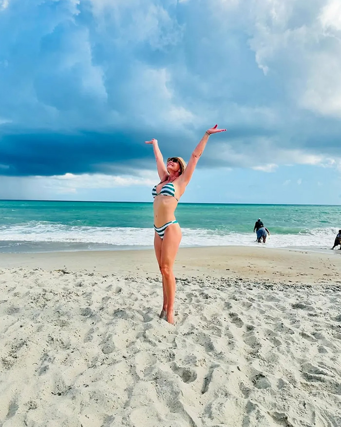 Hollywood actress in a striped bikini on a beach, arms raised, against a stormy sky, months after joining an adult platform. Hollywood actress in a striped bikini on a beach, arms raised, against a stormy sky, months after joining an adult platform.