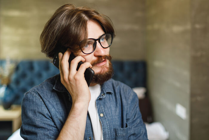 A man with glasses talking on a smartphone, discussing career options in a difficult job market