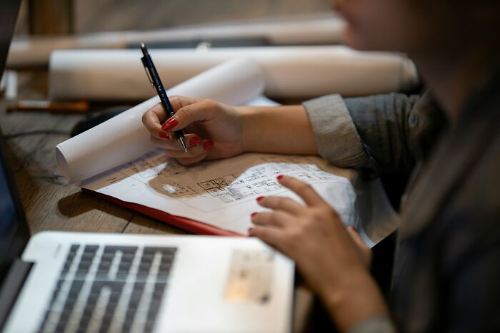 A close-up of an architect sketching plans on paper, representing the struggling job market.