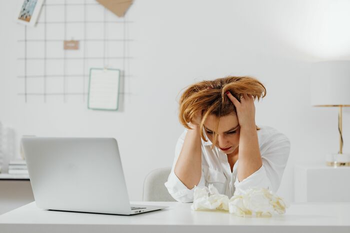 A stressed woman sitting at her desk with a laptop, highlighting the challenges of the current job market