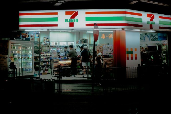 A brightly lit 7-Eleven convenience store at night, with several people inside. Lawyers were shocked by how stupid their clients could be.