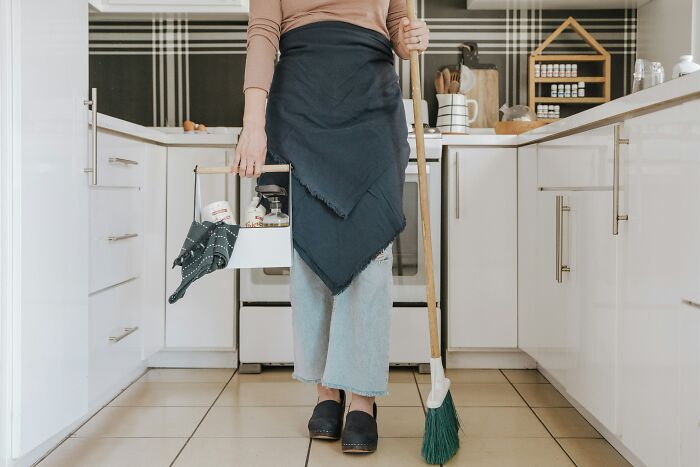 A person in a kitchen with cleaning supplies, showing how to keep spiders out of UK homes. A person in a kitchen with cleaning supplies, showing how to keep spiders out of UK homes.