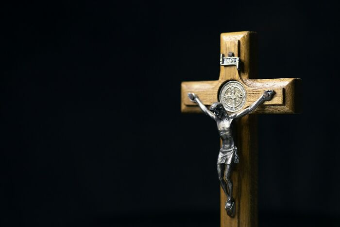 A wooden crucifix with a silver figure of Jesus against a dark background. This represents stupid things people said.