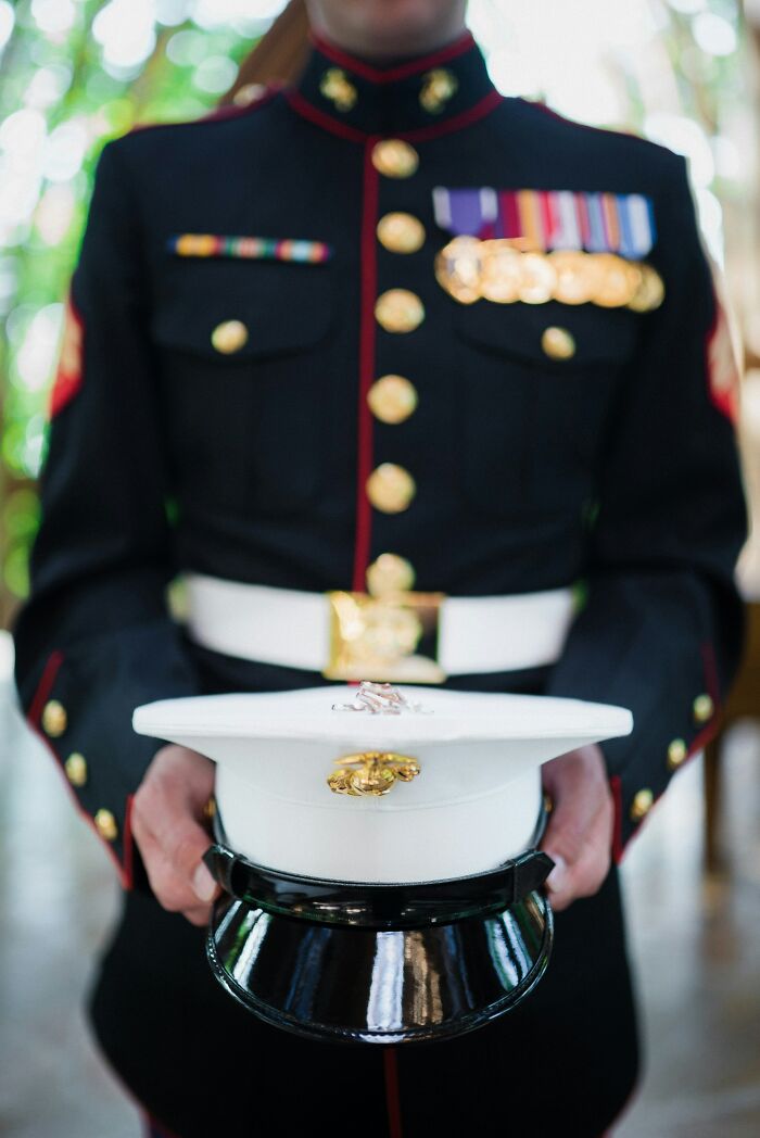 A person in military uniform holding a hat, representing a pain reaction to duty.