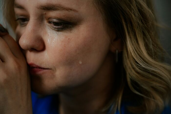 Close-up of a woman crying, a tear rolling down her cheek, representing emotional moments people overheard.