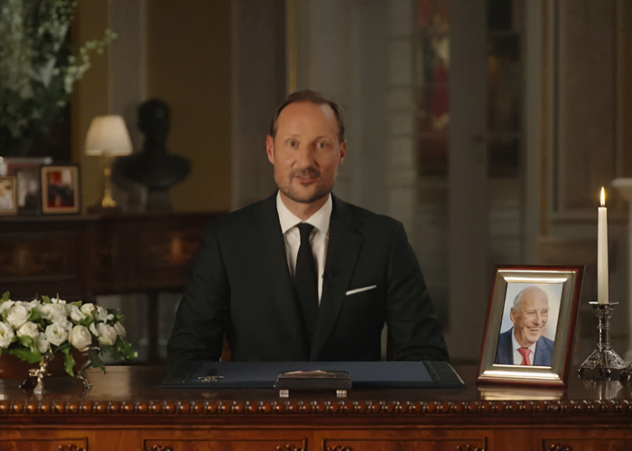A man in a suit at a desk, likely related to the son of Norway's Crown and his crucial role in a royal funeral.