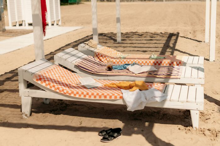 Beach lounge chairs with towels and sandals on sand vacation scene