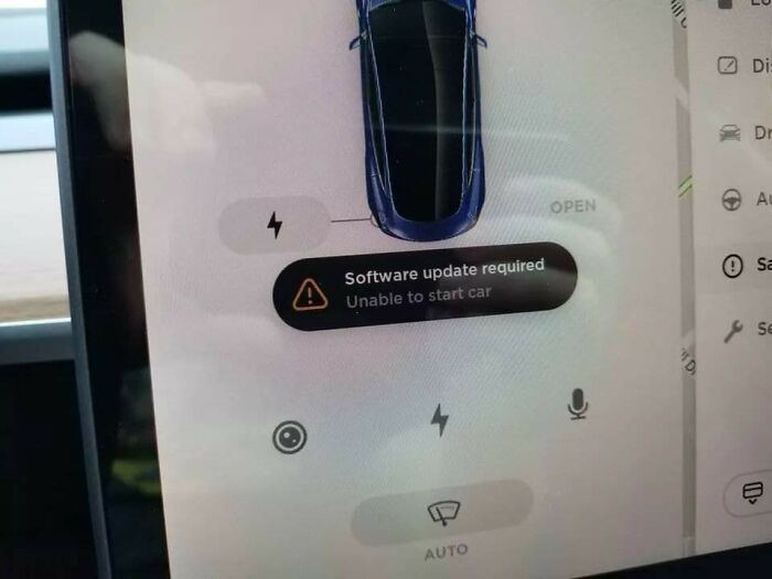 A car screen displaying a software update required warning that prevents starting, a terrible product design