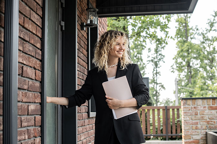 Smiling woman with curly blonde hair holding documents, standing at a pub entrance, dealing with landlord issues and deposit disputes. Smiling woman with curly blonde hair holding documents, standing at a pub entrance, dealing with landlord issues and deposit disputes.