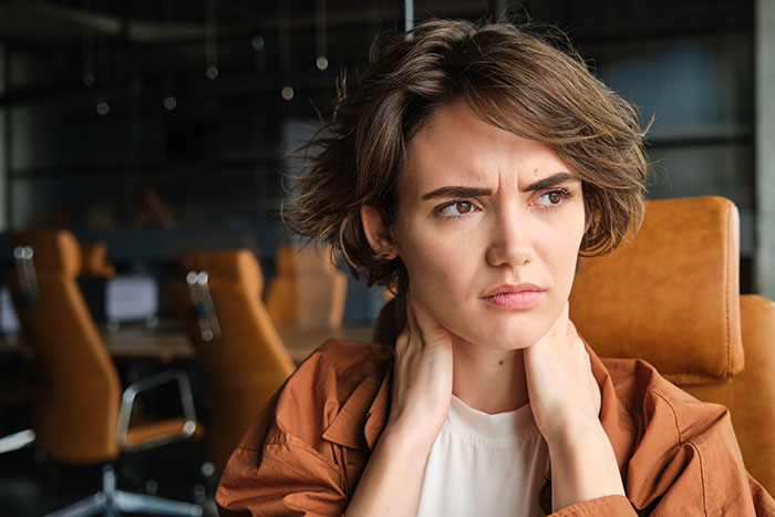 A young woman, representing the GF who said no to driving drunk women, looks worried and holds her neck. A young woman, representing the GF who said no to driving drunk women, looks worried and holds her neck.