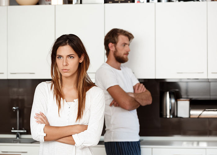 Couple in kitchen upset and avoiding each other showing wife and hubby conflict