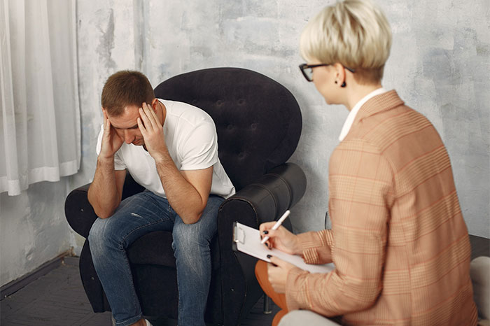 Man in therapy session dealing with emotional stress from wife's ultimatum on sick mom