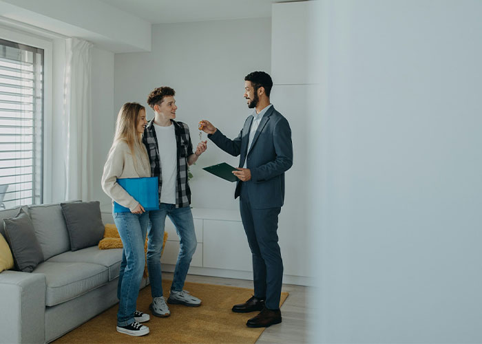 Real estate agent handing keys to couple buying new house