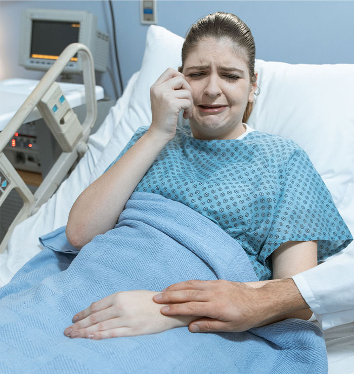 Woman crying in hospital bed with comforting hand, hospital support
