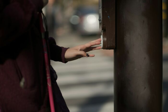 A person pressing a crosswalk button, an example of stupid things people said without realizing how ridiculous.