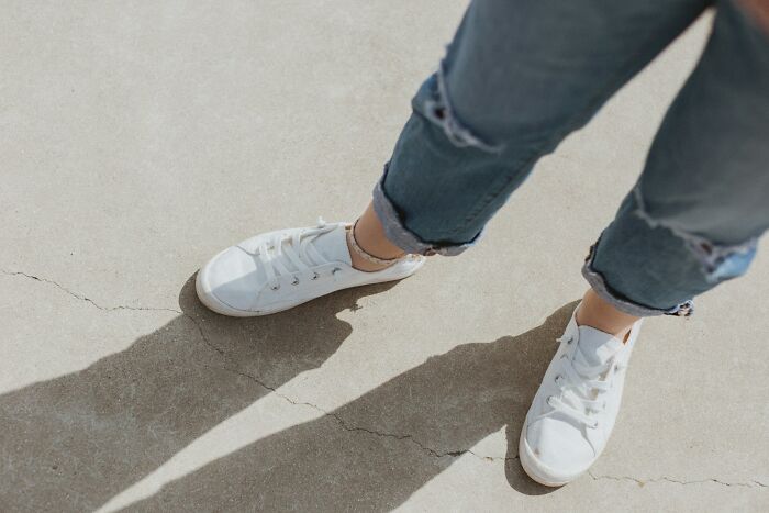 Close-up of feet in white sneakers on pavement, representing body changes in 30s and 40s.