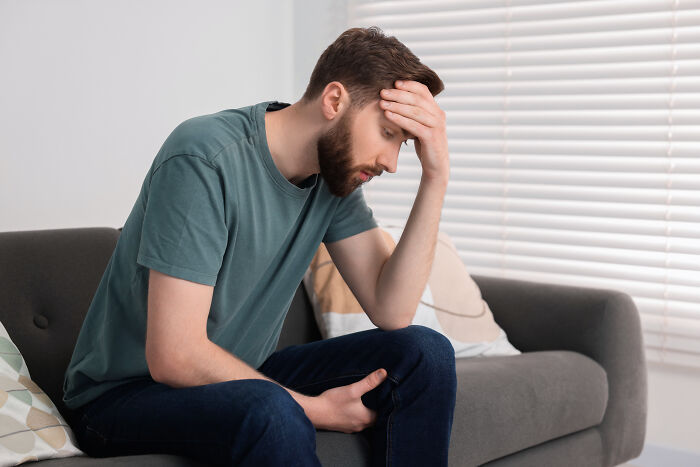 Distressed man on a sofa, contemplating his marriage and the path to divorce.