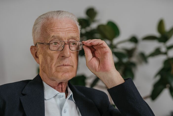 Senior man adjusting his glasses, contemplating over 20 years in a marriage.