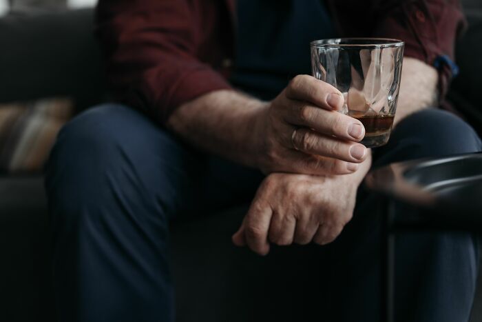 Man holding a glass of whiskey, reflecting on over 20 years in a marriage.