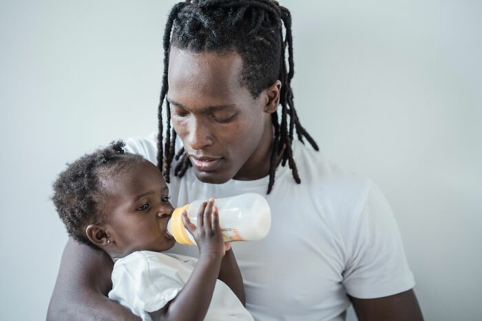 A father feeding his baby, representing the early years of a marriage that may switch after 20 years.