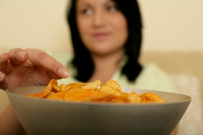 A woman reaching for a potato chip from a bowl, illustrating a possible shift in lifestyle or habits within a marriage.