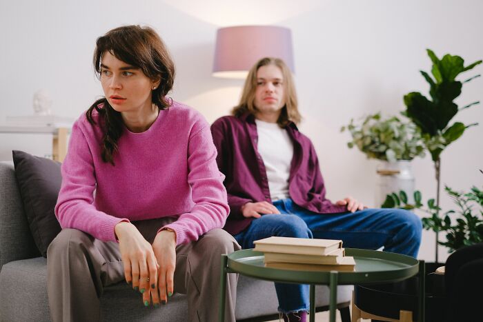 A couple sitting apart on a sofa, looking distant and unhappy, depicting a switch in their marriage.