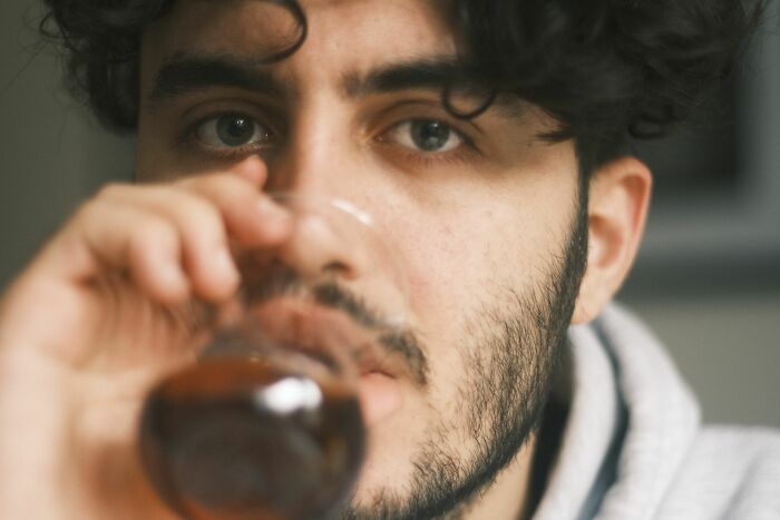 A man with curly hair and a beard looks at the camera while drinking, pondering over marriage after 20 years.