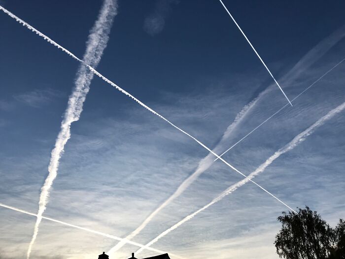 A clear blue sky crisscrossed with airplane contrails, reflecting the unique and often strange childhood beliefs about the world.