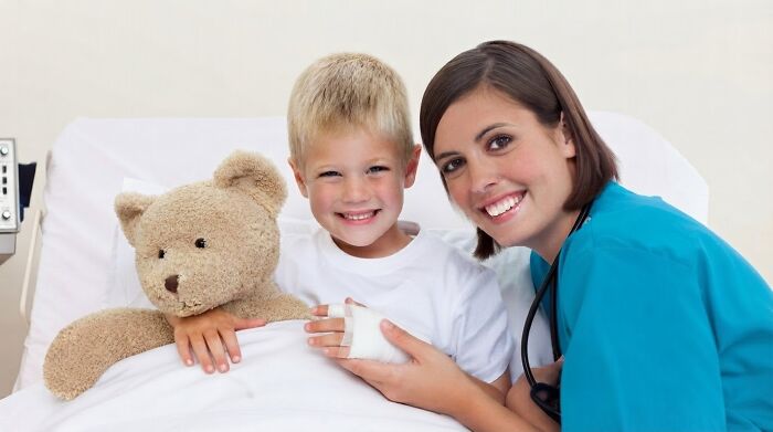 A nurse and a boy with a bandaged arm smiling in a hospital bed, showing pain reactions.
