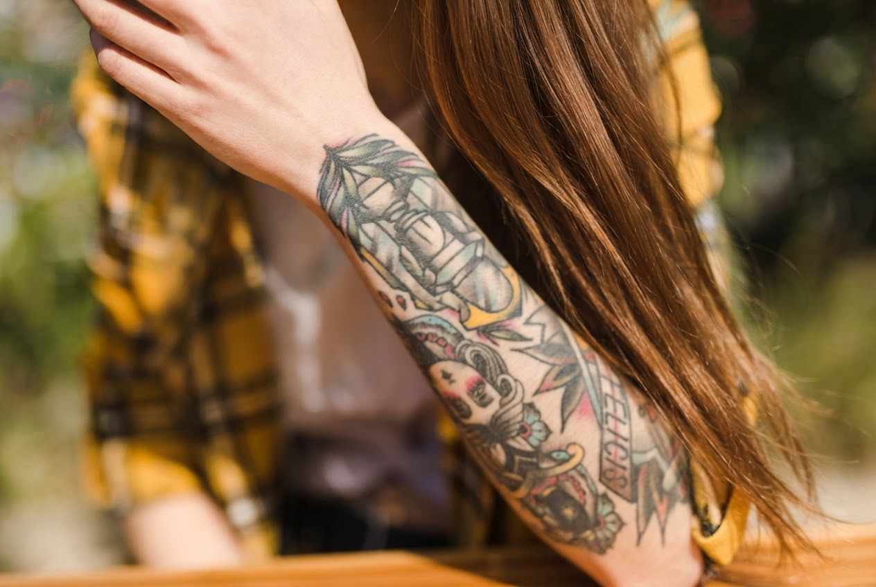 A woman with multiple colorful tattoos on her arm, symbolizing the girlfriend getting tattoos that caused a breakup. A woman with multiple colorful tattoos on her arm, symbolizing the girlfriend getting tattoos that caused a breakup.