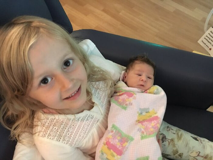 Big sister holding a newborn, highlighting children and parents opening up about experiences.