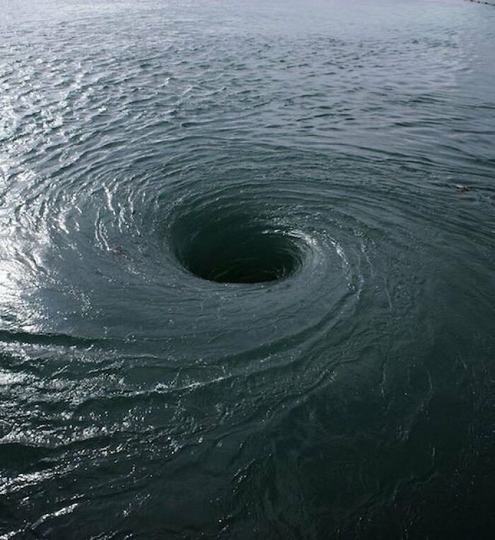 A powerful deep whirlpool forming a dark hole in the ocean