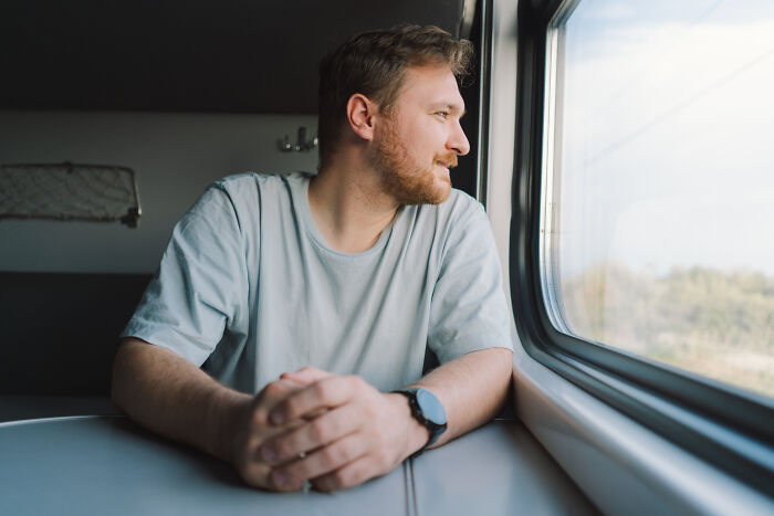 Man looking out train window enjoying vacation travel