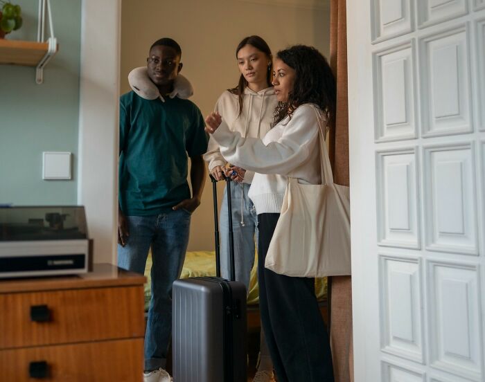 Three people with luggage arriving for an Airbnb stay, seemingly discussing check-in procedures with a host. Three people with luggage arriving for an Airbnb stay, seemingly discussing check-in procedures with a host.