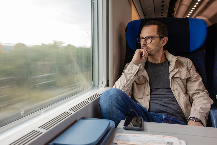 A man sitting on a train staring out the window, illustrating the theme of subtle sexism
