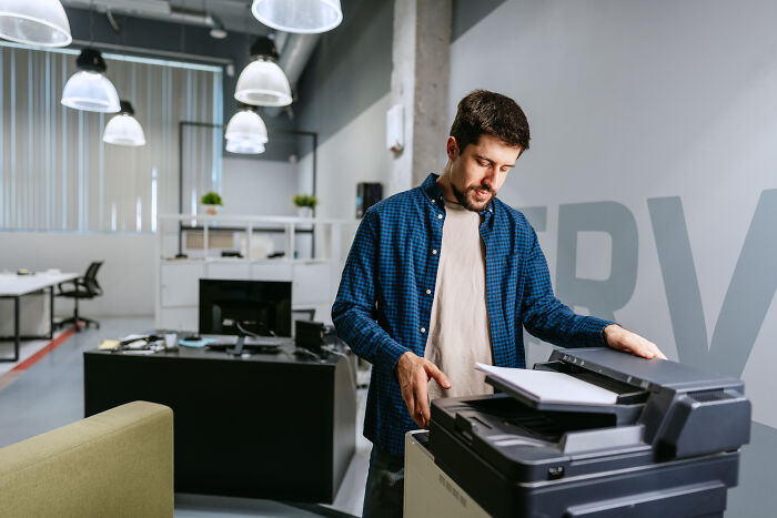 A man working at a copier machine in an office, potentially feeling marriage regrets
