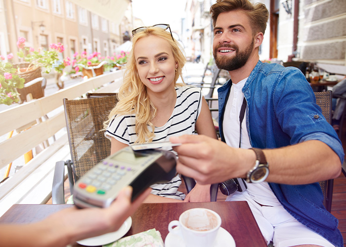 A smiling man paying the bill for a woman, showing how men should treat women on dates.