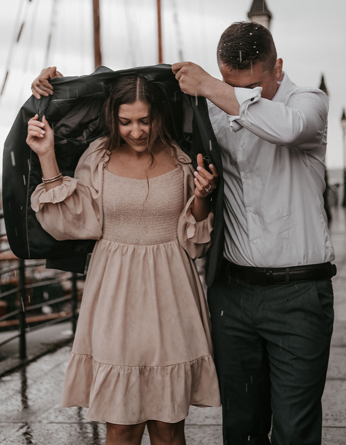 A man holding his jacket over a woman in the rain, illustrating how men should treat women with care.