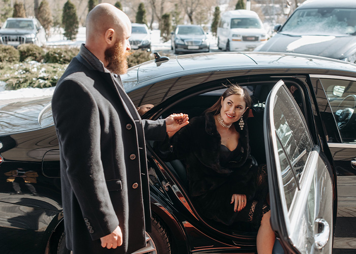 A gentleman opening a car door and offering a hand to a woman, showing classic chivalry in relationships.
