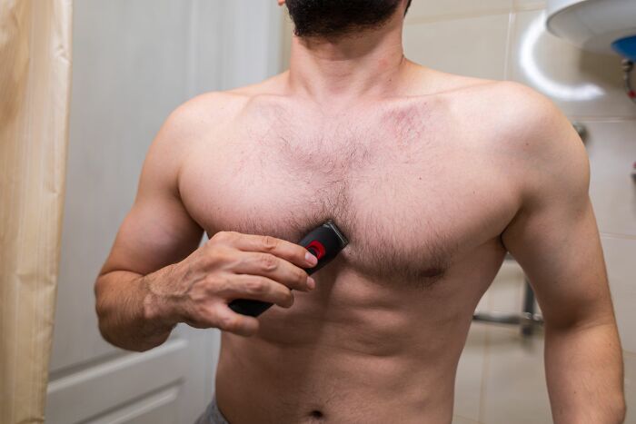 A man shaving his chest hair, preparing for weddings and romance