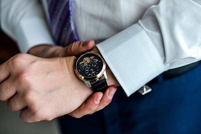 A man adjusts an expensive watch, one of the surprising things wealthy people buy.
